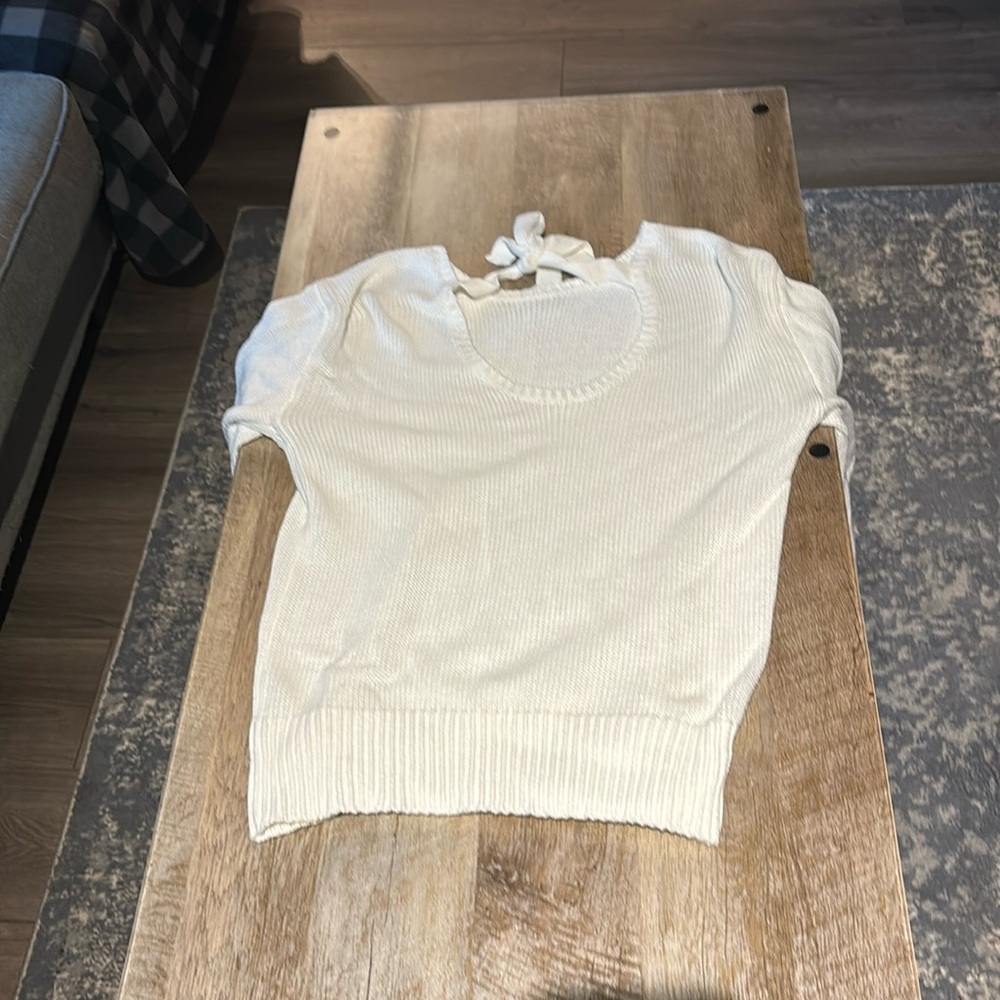 White sweater with tie in between shoulders